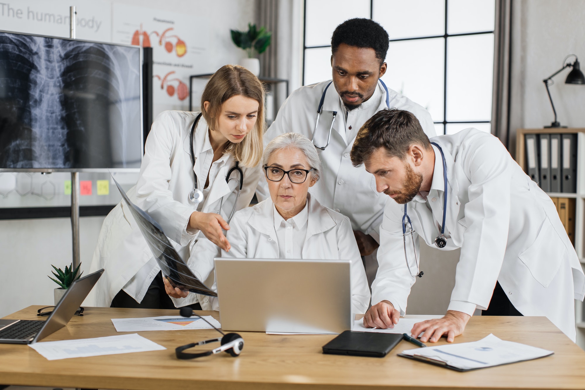 Group of four multiethnic medics having consilium in clinic